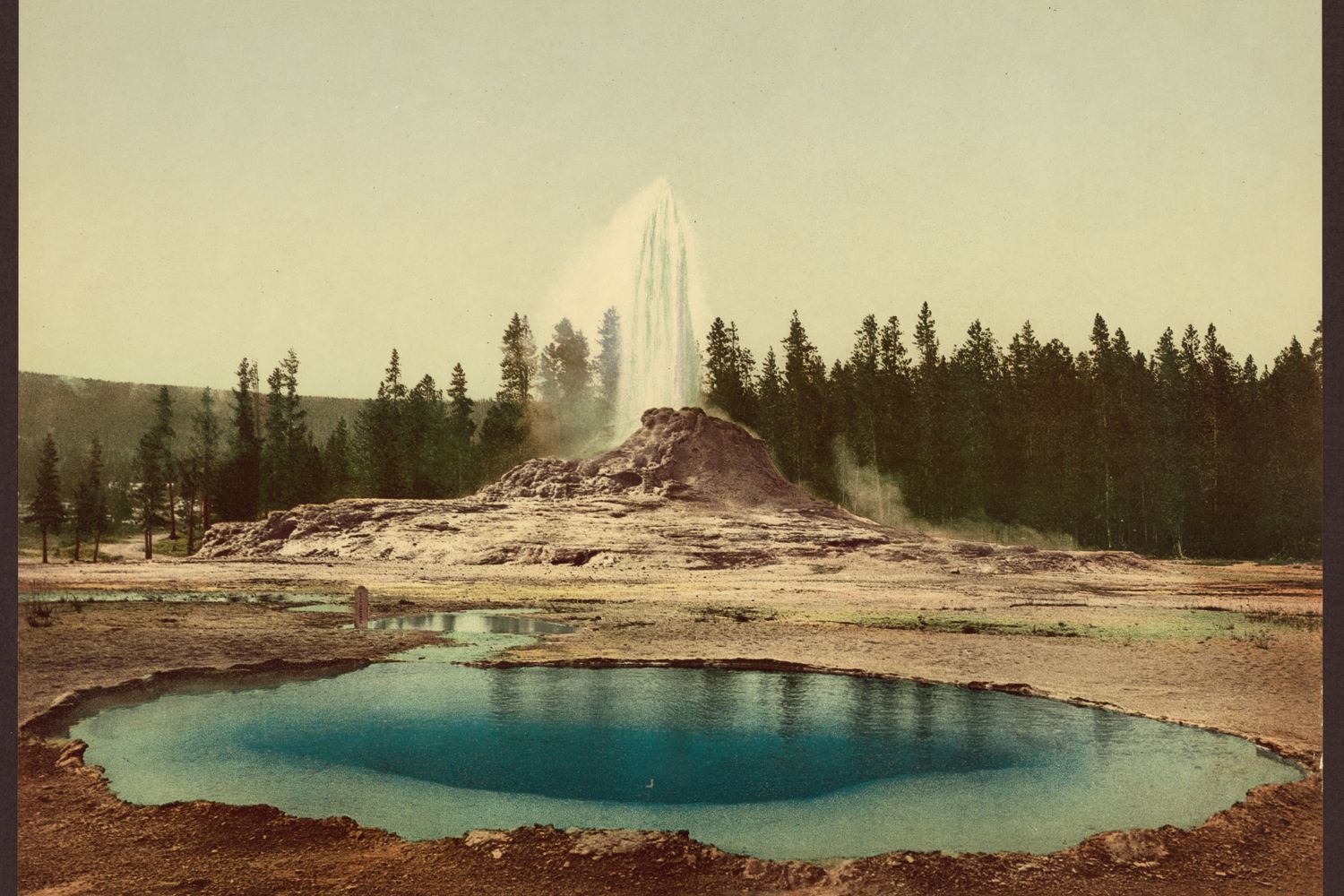 Castle Geyser's stone cone with a plume of steam against the sky, in an old photograph.